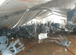 Tenda branca combrindo cadeiras derrubas no chão após chuva.